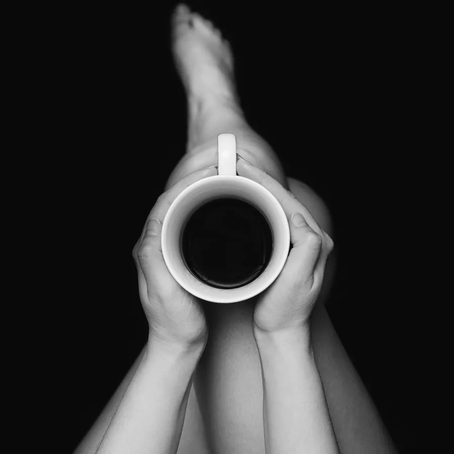 czarno-biała fotografia kubek z kawa na kobiecym kolanie autor; Artur Sobieraj fotograf; artursobieraj_com